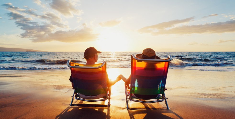 Couple sitting in chairs on the beach looking at sunset